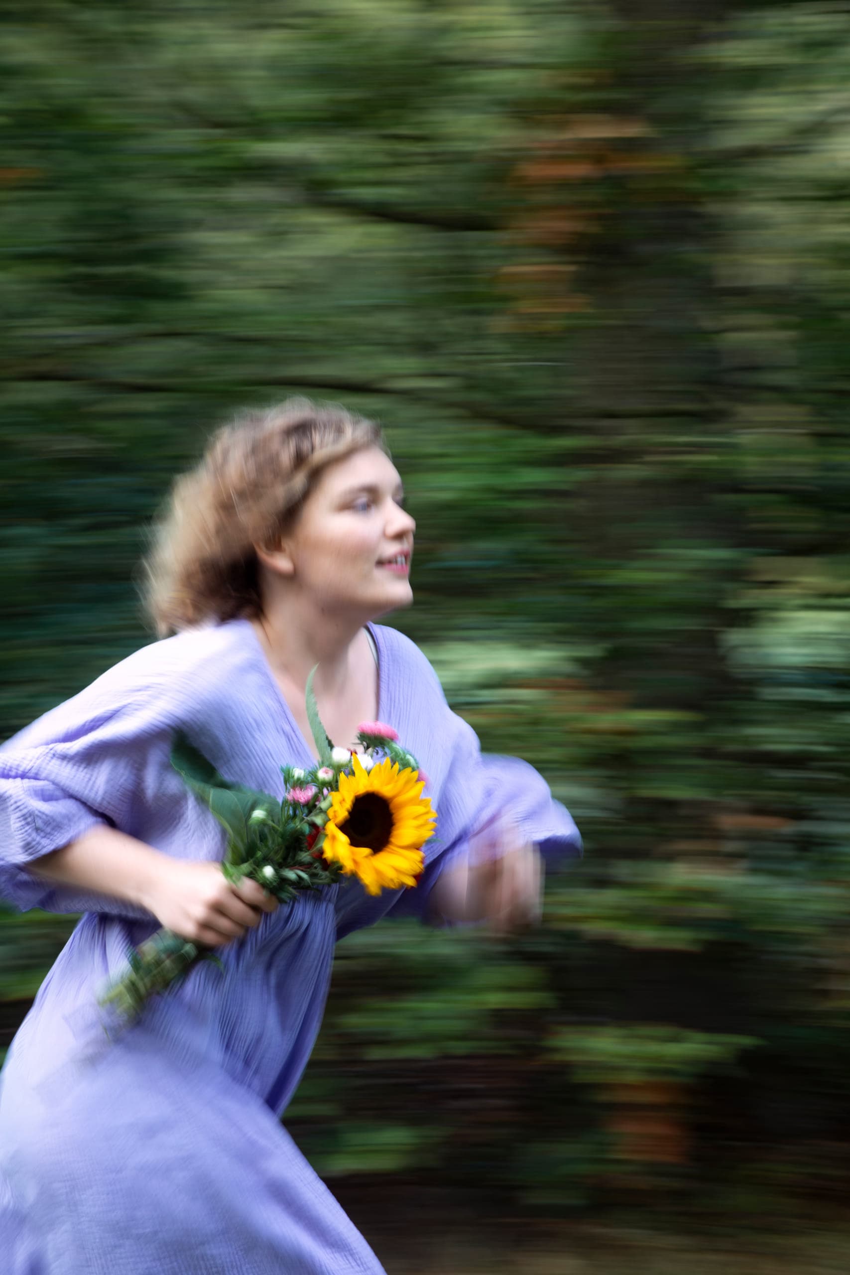 Nina rent door het bos met een zonnebloem in haar hand