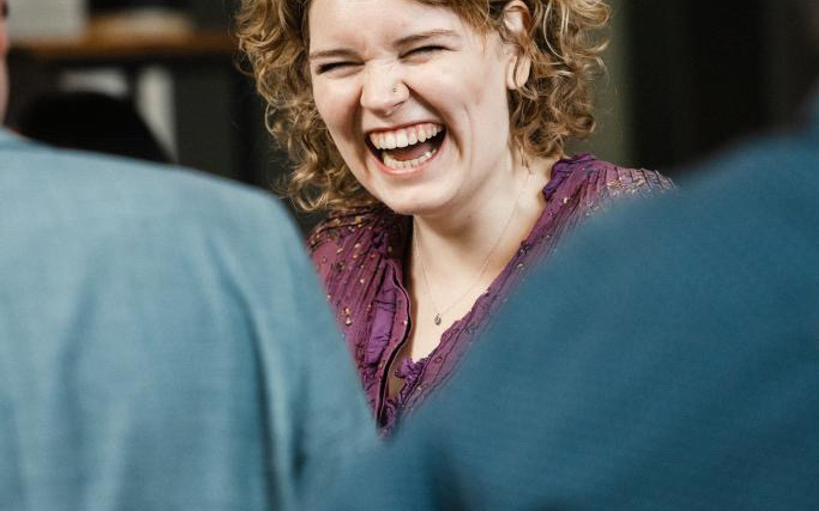 NinaLynn lacht hartelijk, met twee gasten op de voorgrond