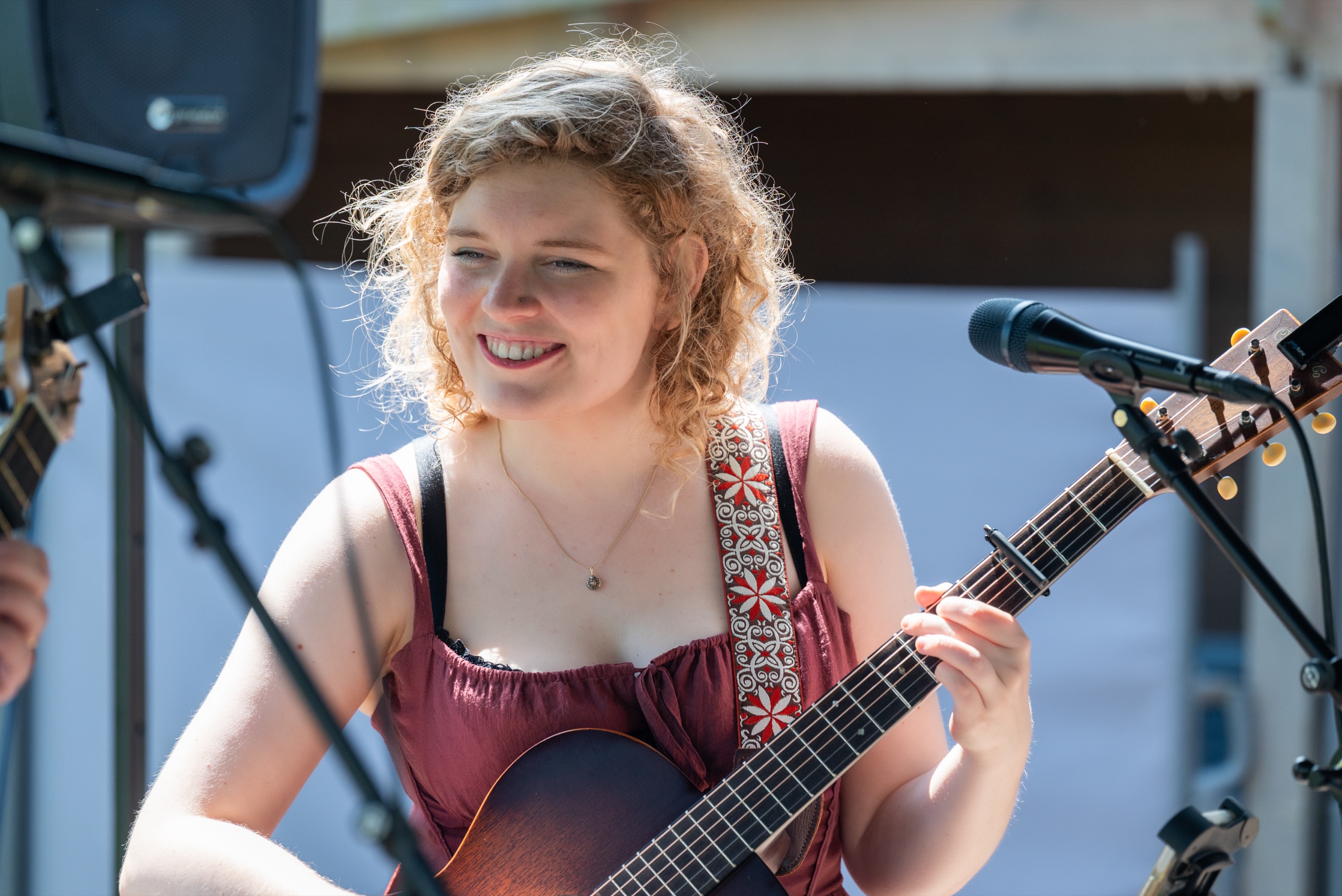 Close-up van NinaLynn die lacht terwijl ze gitaar speelt, in tegenlicht