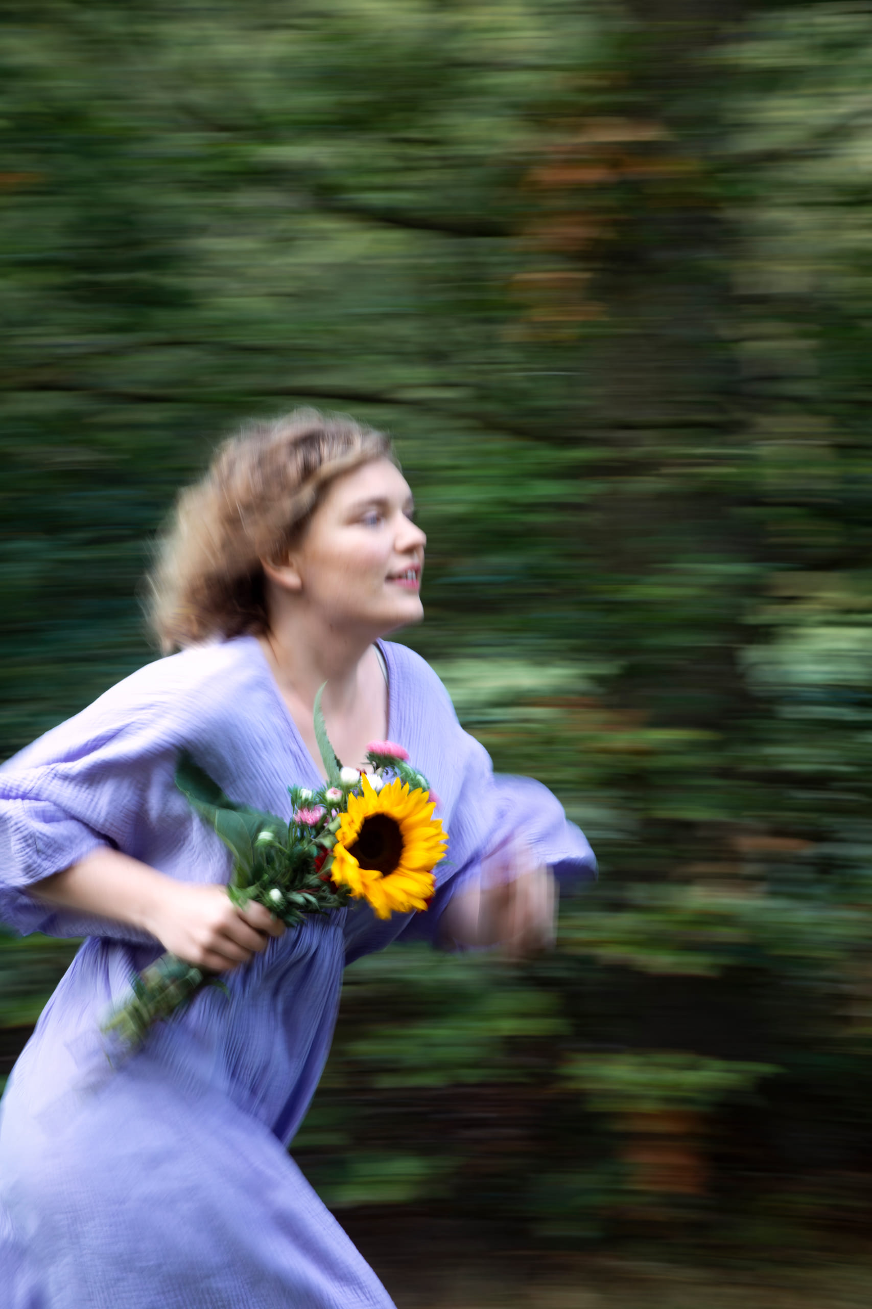 Nina rent door het bos met een zonnebloem in haar hand